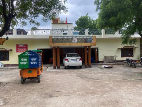 Un coche aparcado en un estacionamiento frente a un edificio. en Abhijeet, en Rāe Bareli