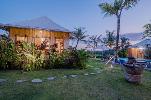 a house with a yard with a tree and a swing at Paddy's Glamping Managed by Manara in Canggu