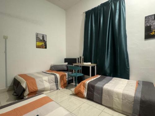 a room with two beds and a desk in it at Taman Sri Utama Gurun 