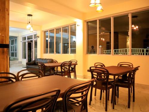a dining room with tables and chairs and windows at Ess-PHLYNDA in Lāitlyngkot