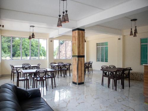 a dining room with tables and chairs and windows at Ess-PHLYNDA in Lāitlyngkot