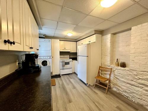 a kitchen with white appliances and a chair in it at Hiltz House Cellar Suite Near Halifax Ferry in Halifax