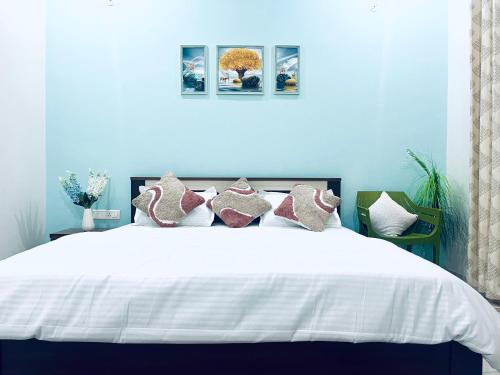 a blue bedroom with a large white bed with pillows at Next Little Door in Dehradun