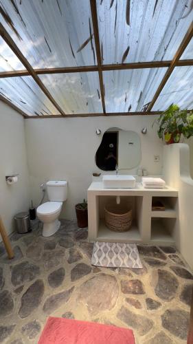 a bathroom with a white toilet and a sink at Santai House in Tetebatu
