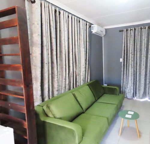 a living room with a green couch in front of a window at The River Boutique Inn in Lobamba
