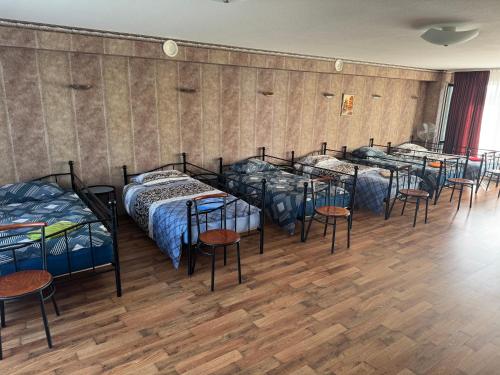 a group of beds in a room with wooden floors at Baskervilu Muiža in Sērenes
