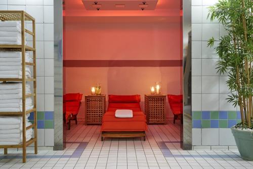 a waiting room with red chairs and tables at H+ Hotel Köln Hürth in Hürth