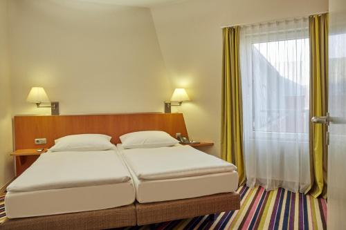 a bedroom with a large bed with a window at H+ Hotel Köln Hürth in Hürth