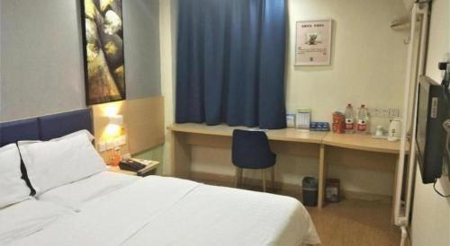 a bedroom with a bed and a desk with a blue curtain at 7 Days Inn Jinan Changqing Jingshi West Road Center in Jinan