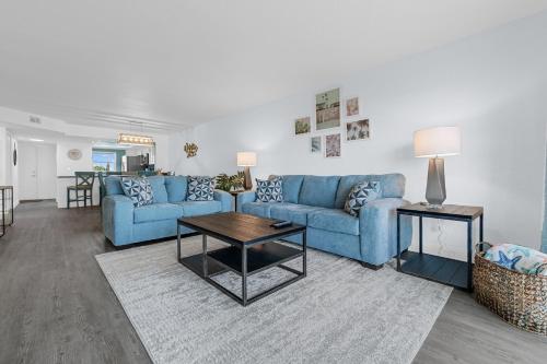 a living room with blue couches and a table at Boardwalk 205 in Cocoa Beach