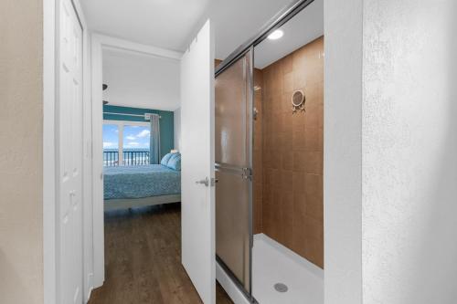 a bathroom with a walk in shower next to a bedroom at Boardwalk 205 in Cocoa Beach