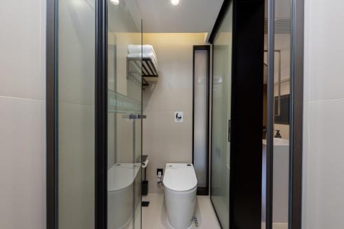 a bathroom with a toilet and a glass wall at Leshan Manfu Hotel in Leshan