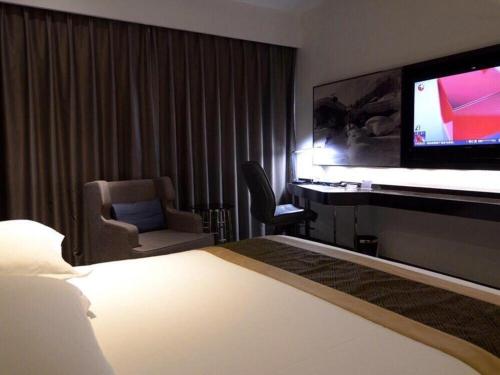 a hotel room with a bed and a flat screen tv at Harbin Splendent Hotel in Harbin