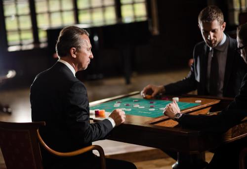 two men in suits sitting at a table playing poker at Szidónia Castle in Röjtökmuzsaj