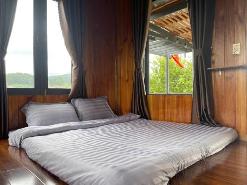 a large bed in a room with two windows at Đà Lạt Thiên Vương Homestay in Lạc Dương