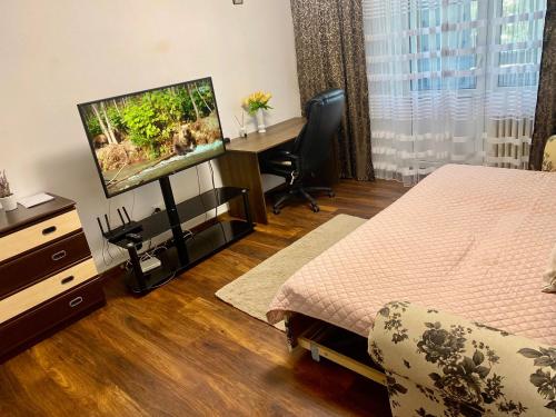 a bedroom with a bed and a desk with a television at Garsoniera ultracentrală1 in Piteşti