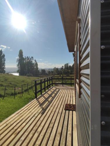 a wooden deck with a view of a field at Cabaña privada con acceso a playa in Castro