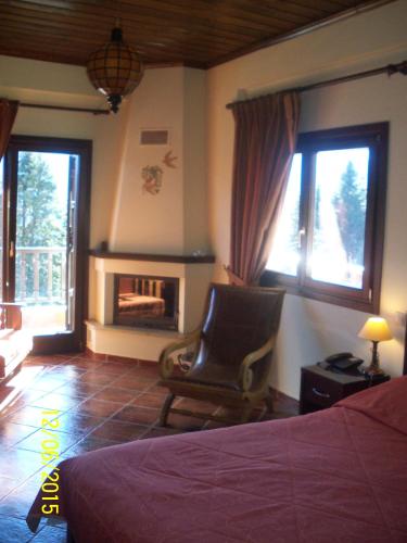 a bedroom with a bed and a chair and a fireplace at Ξενοδοχείο ΜΑΓΚΙΩΣΗ in Neraïdochóri