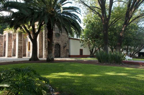 a courtyard with palm trees and a building at Hacienda Jurica by Brisas in Querétaro