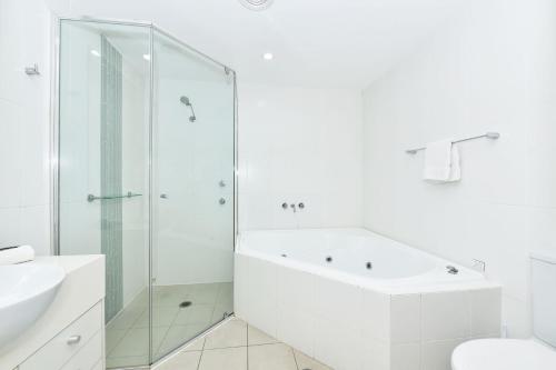 baño blanco con bañera y ducha acristalada en Pacific Blue Unit 175 Dual Swim Up, en Salamander Bay