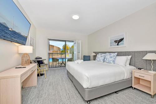 Un dormitorio con una cama y un escritorio y una ventana. en Pacific Blue Unit 175 Dual Swim Up, en Salamander Bay