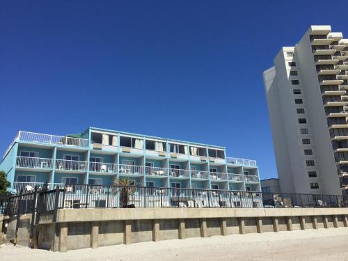 a building on the beach next to two buildings at Garden City Inn in Myrtle Beach