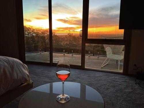 a glass of wine sitting on a table in front of a window at Cape Schanck Golf and Ocean Views Holiday Villa in Cape Schanck