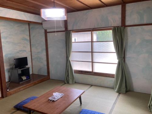 a living room with a table and a window at Yado KONAMI in Shimoda