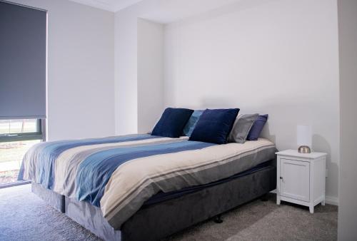 バッセルトンにあるSunset Shores 4BR Pool Retreat in Busseltonの白いベッドルームのベッド1台(青い枕付)