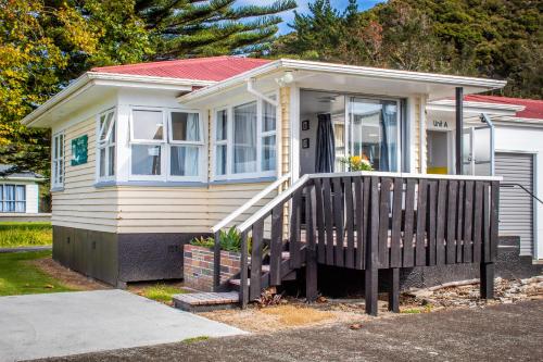 une petite maison jaune avec une terrasse couverte en bois dans l'établissement Waitangi Beach Unit A, à Paihia