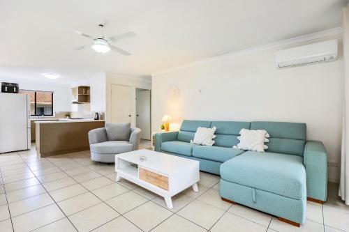 a living room with a blue couch and a table at Arlia Sands Apartments in Hervey Bay