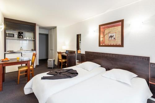 a hotel room with two beds and a table and a kitchen at Aparthotel Adagio Access Toulouse Jolimont in Toulouse