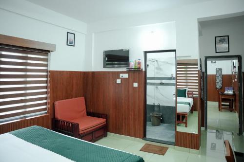 a bedroom with a bed and a chair and a mirror at TREE 9 COCHIN AiRPORT HOTEL in Nedumbassery