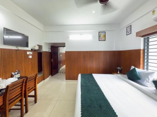 a bedroom with a bed and a desk and a tv at TREE 9 COCHIN AiRPORT HOTEL in Nedumbassery