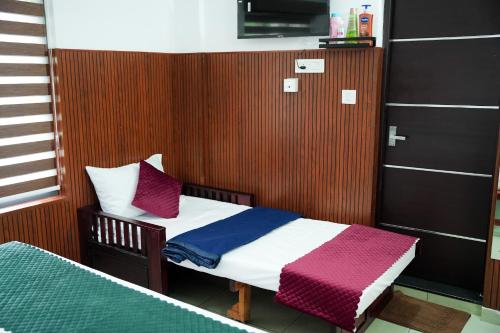 a small bedroom with a bed with purple and white sheets at TREE 9 COCHIN AiRPORT HOTEL in Nedumbassery
