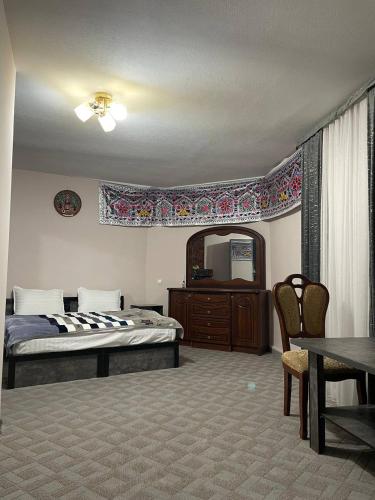 a bedroom with a bed and a table and a mirror at Kifoyat Hotel in Samarkand