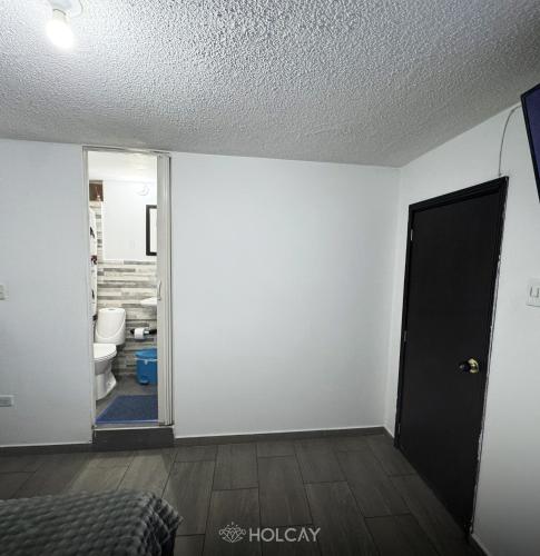 an empty room with a door leading to a bathroom at Hospedaje Holcay in Bogotá