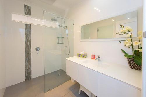 a bathroom with a sink and a glass shower at Sea Renity On Earnshaw 3BR Beachside Bliss in Broadwater
