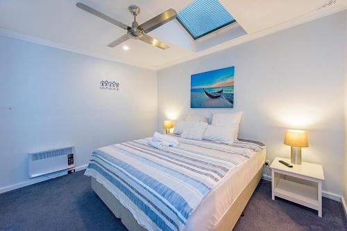 a bedroom with a bed and a ceiling fan at Sea Renity On Earnshaw 3BR Beachside Bliss in Broadwater