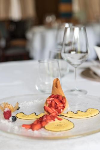 a white plate with food on a table with wine glasses at Grand Hotel Tamerici & Principe in Montecatini Terme