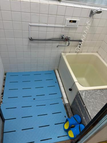 a bathroom with a tub and a blue floor at 栄子ハウス in Iwatsuki