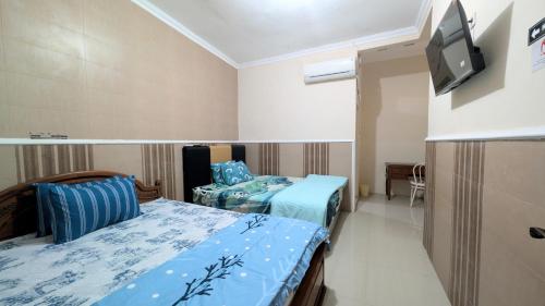 a room with two beds and a flat screen tv at Surabaya Homey Dharmahusada Syariah in Surabaya