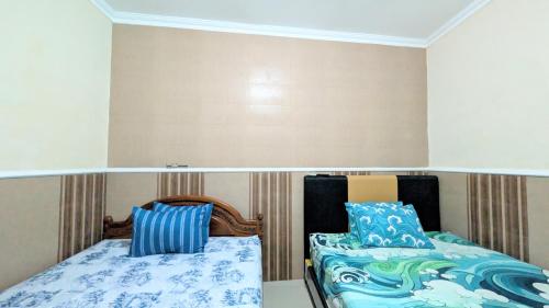 a room with two beds with blue pillows at Surabaya Homey Dharmahusada Syariah in Surabaya