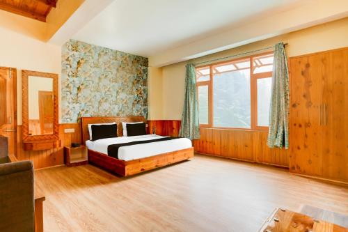 a bedroom with a bed and a large window at Hotel O Model Town Road in Manāli