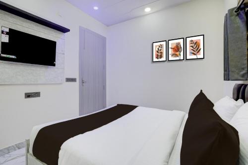 a bedroom with a bed and a tv on the wall at Super Collection O Rohini Sector 21 Formerly Shelter Inn in New Delhi