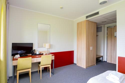 a hotel room with a desk with two chairs and a bed at Aqua-Zdrój in Wałbrzych