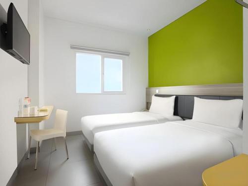 two beds in a room with a green wall at Amaris Hotel Ambon in Ambon