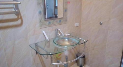 a glass sink in a bathroom with a mirror at Garuda Hotel Pontianak in Pontianak