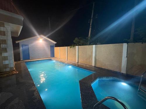 a swimming pool lit up at night with lights at Golden Nest Farms 3BHK Private Pool by Homeyhuts in Venkatāpur