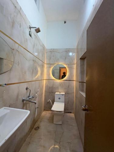 a bathroom with a toilet and a sink and a mirror at Golden Nest Farms 3BHK Private Pool by Homeyhuts in Venkatāpur